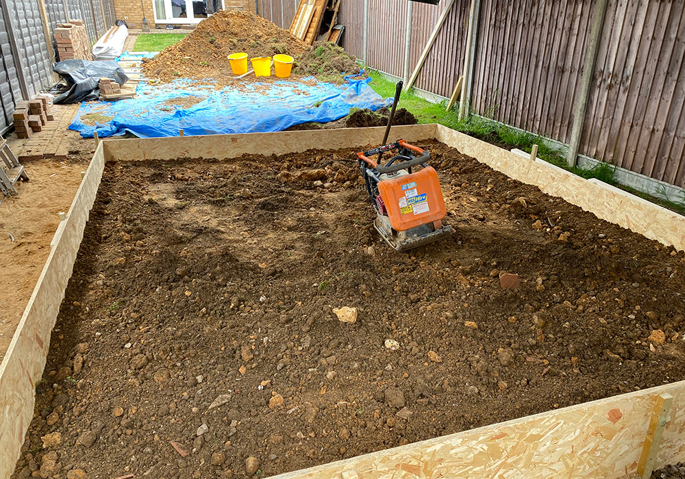 Compactor on the prepared sub-base within timber formwork