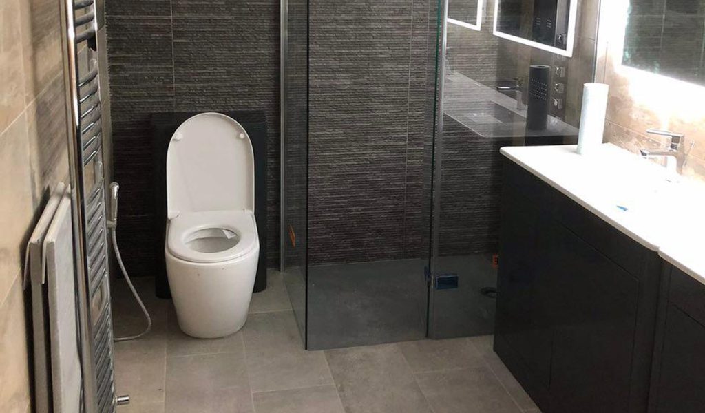 Completed bathroom with glass shower enclosure, toilet and vanity