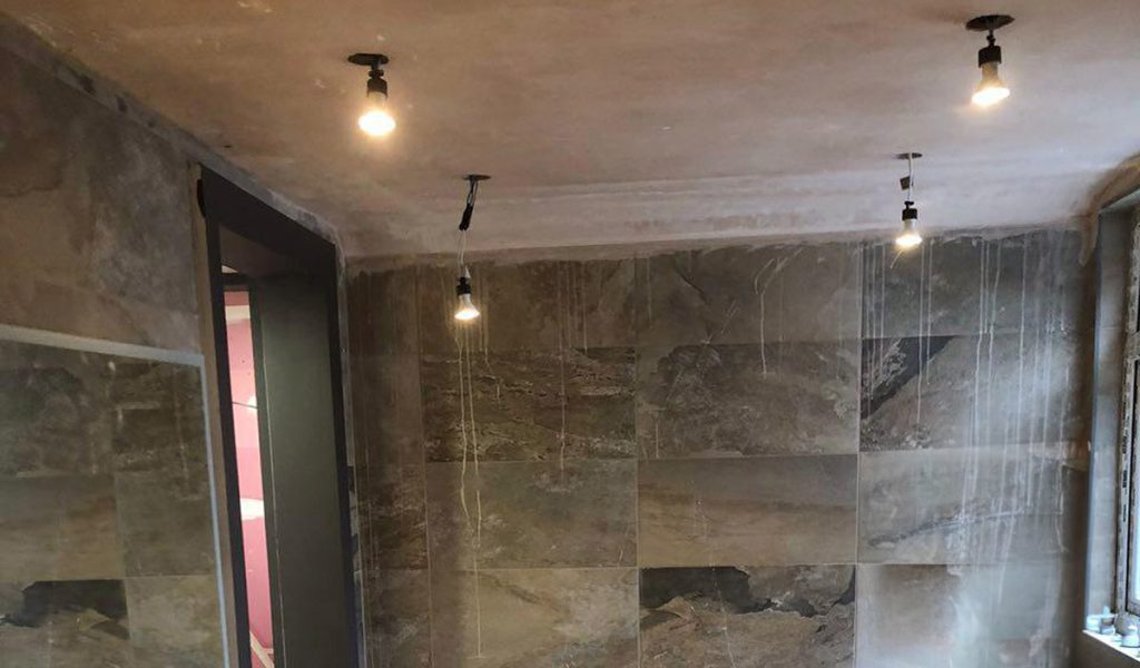 Bathroom interior during finishing, with ceiling lights and installation materials